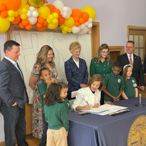 Gov. Kim Reynolds surrounded by HSA Des Moines students as she signs a new bill into law